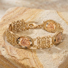 Gold bracelet with rose designs on a textured stone surface
