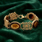 Gold bracelet with brown stones on a green fabric background