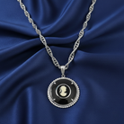 Silver necklace with a black cameo pendant on blue fabric