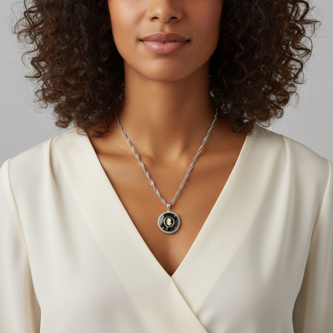 Woman wearing a necklace with a white top and a black cameo pendant against a neutral background