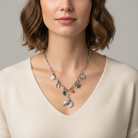 Woman wearing a necklace with various charms against a neutral background