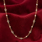 Gold tone necklace with clear crystals and white faux pearls resting on red velvet fabric