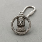 Silver keychain with a cat design on a gray background