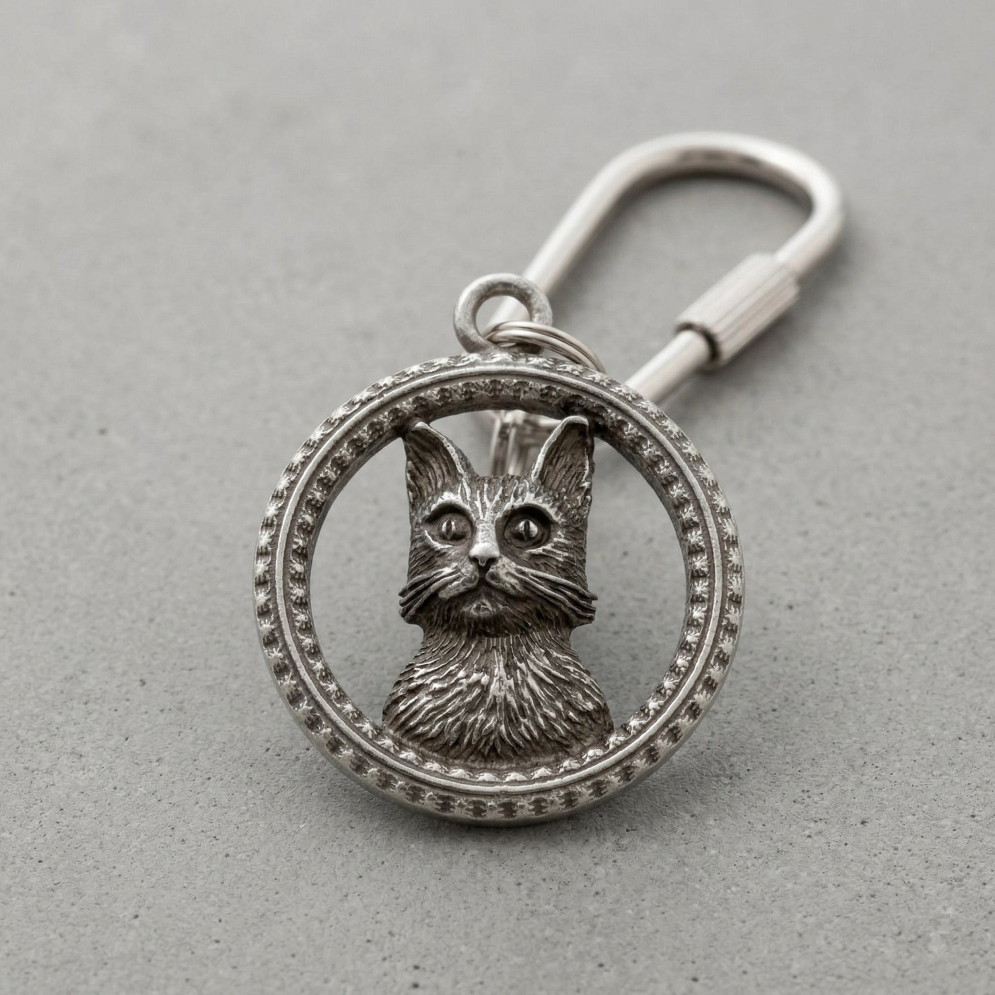 Silver keychain with a cat design on a gray background