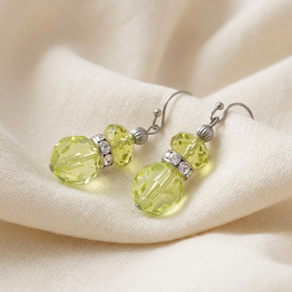 Dual Elegance Light Green Crystal Drop Earrings resting on a cream cloth surface