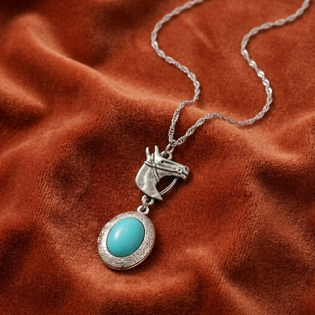 Silver horse head pendant necklace with a turquoise stone resting on dark red fabric