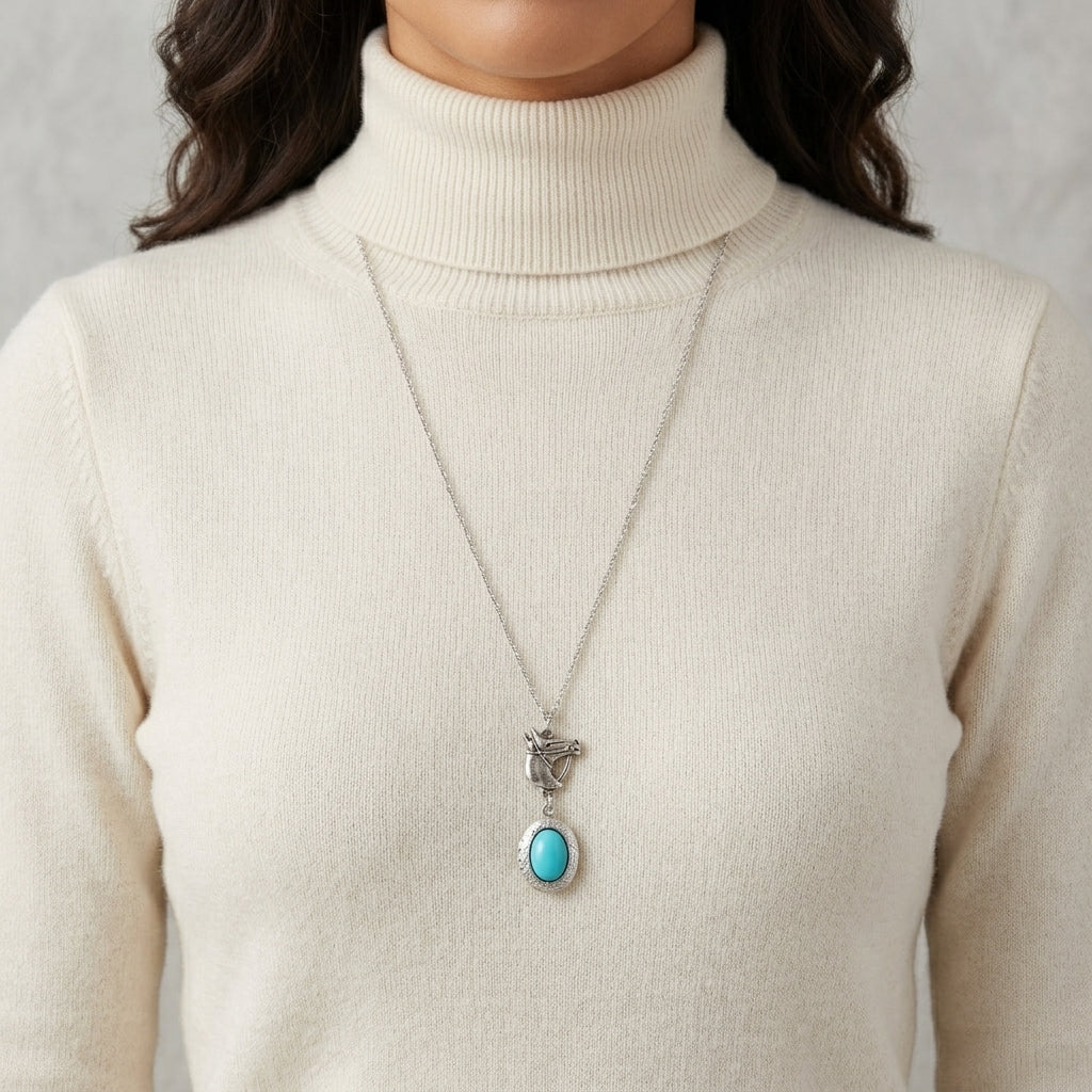 Person wearing a necklace with a turquoise stone and silver horse head pendant on a plain background