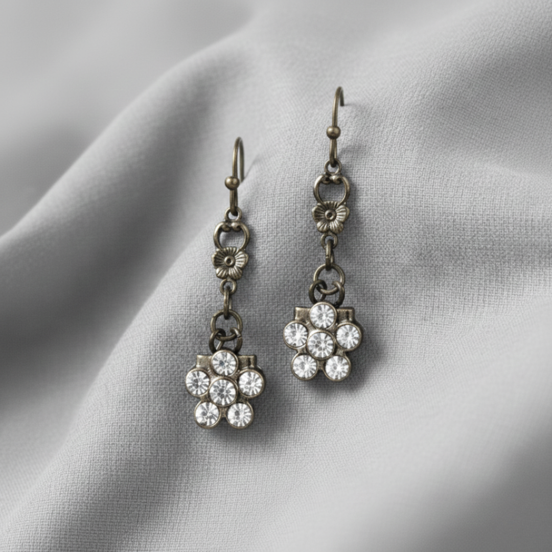 Pair of floral earrings with crystal details on a light fabric background