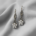 Pair of floral earrings with crystal details on a light fabric background
