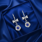 Silver earrings with blue gemstones on a blue satin background