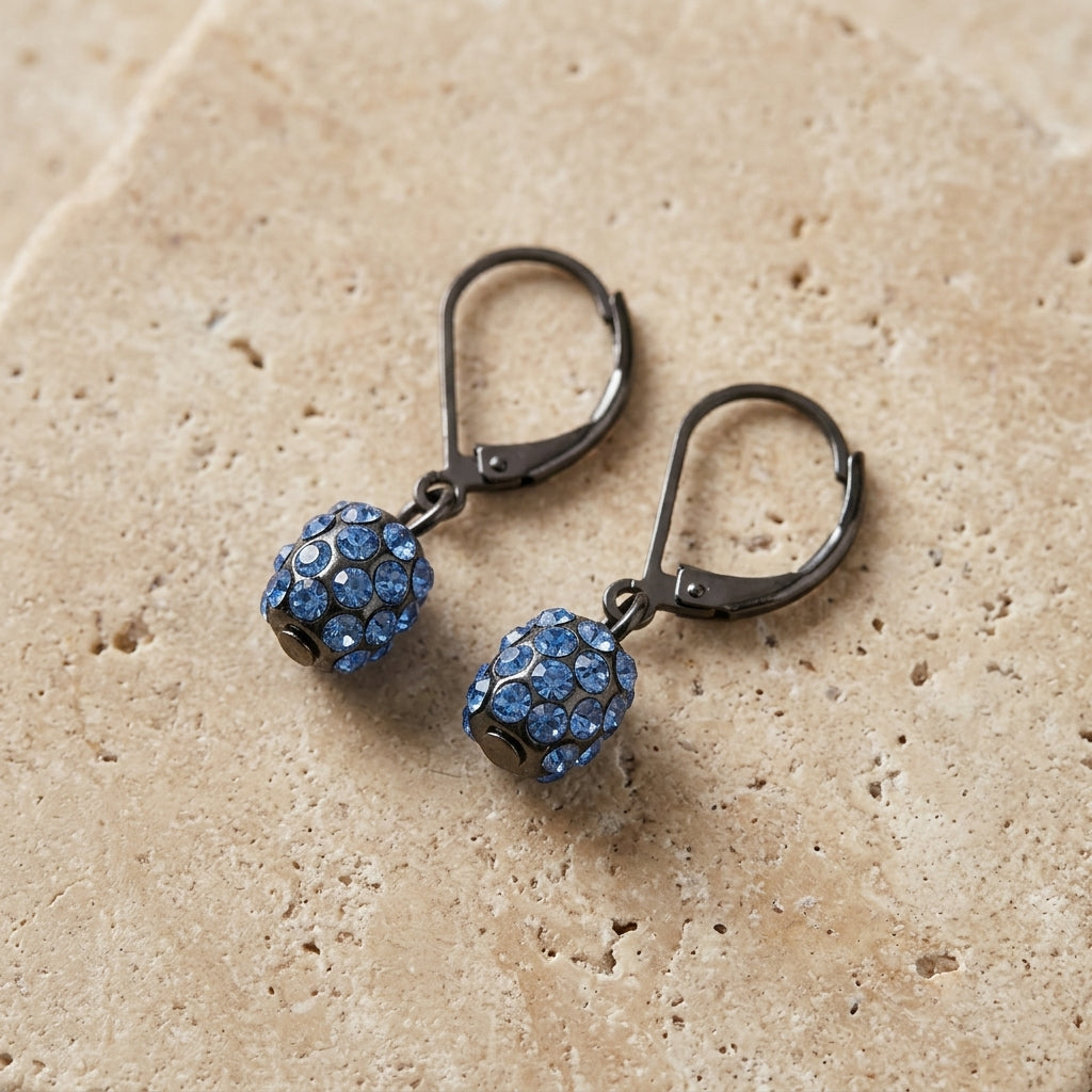 Jet Black Light Sapphire Crystal Fireball Drop Earrings on beige stone surface