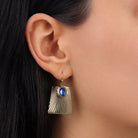 Close up of a model's ear wearing Blue Oval Bead Corrugated Rectangle Drop Earrings
