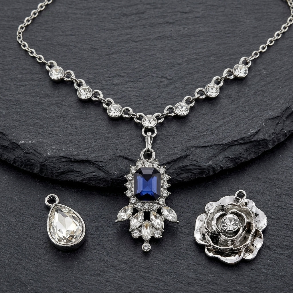 Silver tone necklace set with three different pendants and a blue crystal on a textured dark stone surface