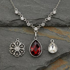Necklace with three interchangeable pendants on a dark stone surface