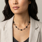 Woman wearing a necklace with black beads against a neutral background