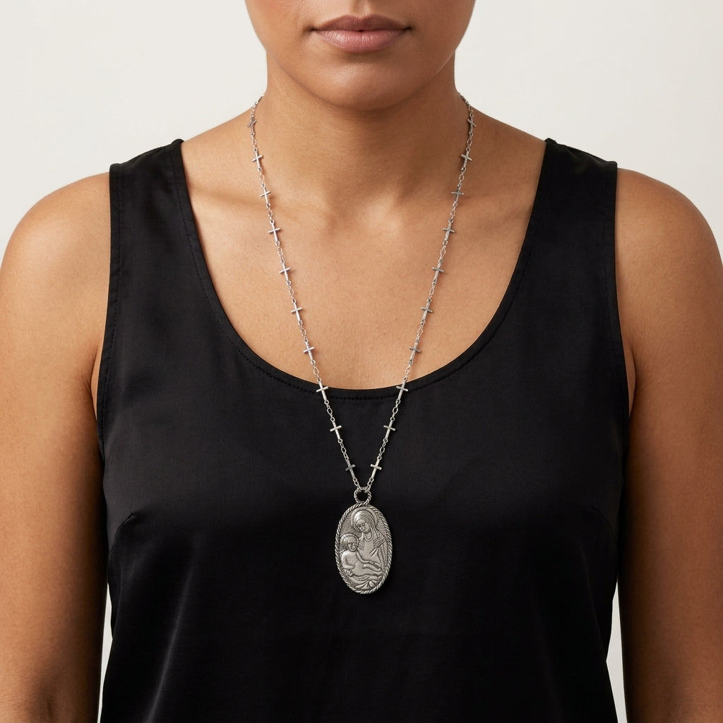 Person wearing a black sleeveless top with a silver necklace featuring a Madonna and Child pendant.