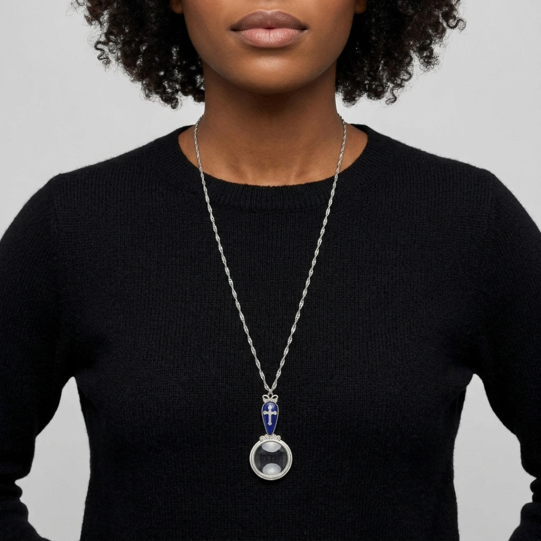 Person wearing a black sweater with a necklace featuring a large magnifying glass and cross pendant.