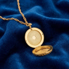 Gold locket opened on a blue fabric background