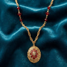 Gold necklace with a red Star of Bethlehem pendant on a blue velvet background