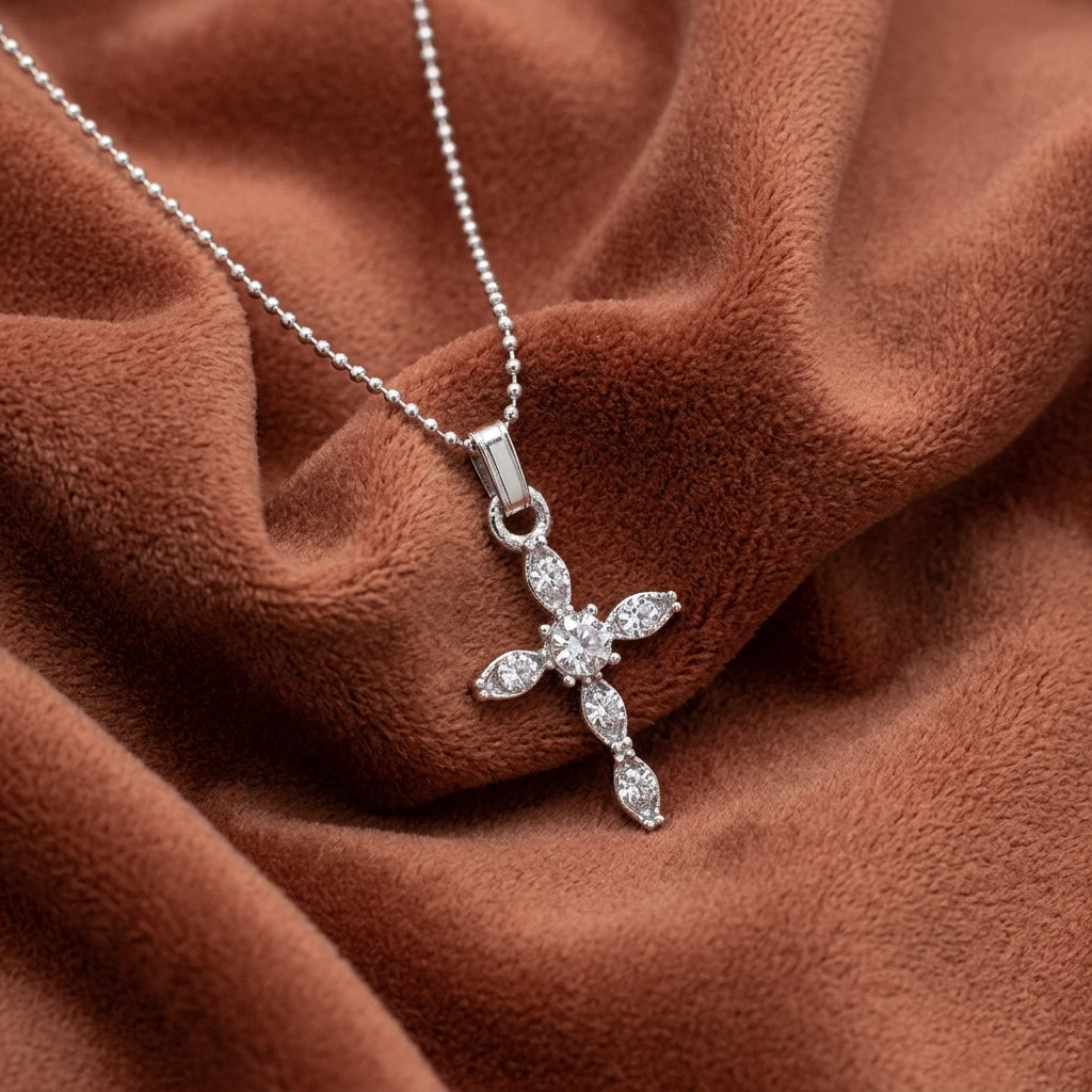 Silver cross pendant necklace with dazzling crystals on a brown fabric background