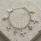 Silver bracelet with various cross charms on a concrete surface