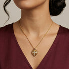 Gold heart-shaped locket necklace worn by a person with a neutral background