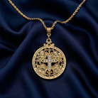 Gold necklace with a detailed pendant on a blue fabric background