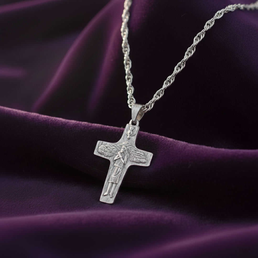 Silver cross pendant necklace on a purple fabric background