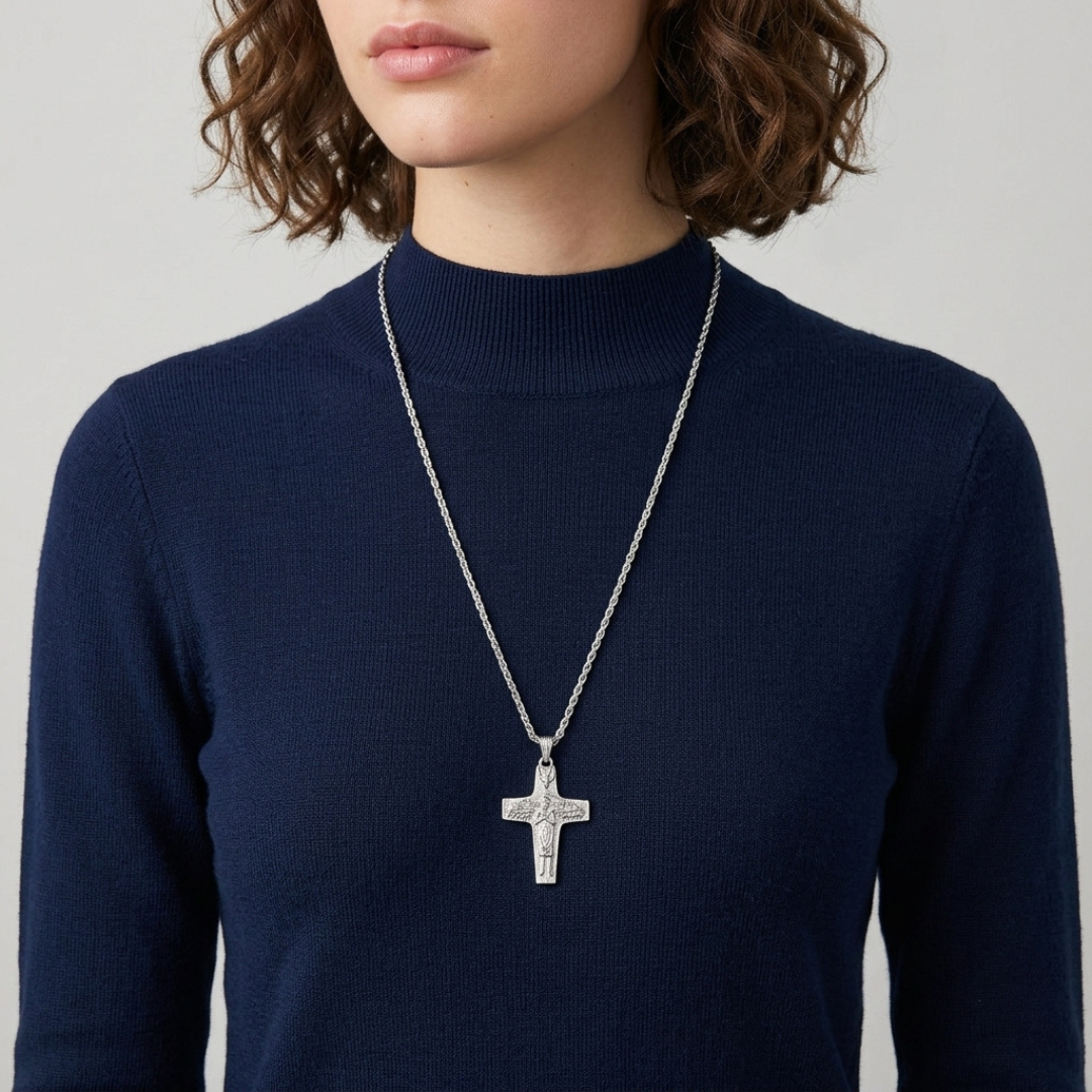 Person wearing a silver cross necklace on a plain background
