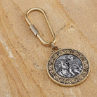 Decorative keychain with a circular emblem of Saint Christopher holding Baby Jesus on a beige stone surface