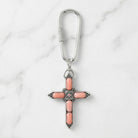 Cross-shaped keychain with pink stones on a marble background