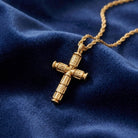 Gold cross pendant on a chain against a blue fabric background