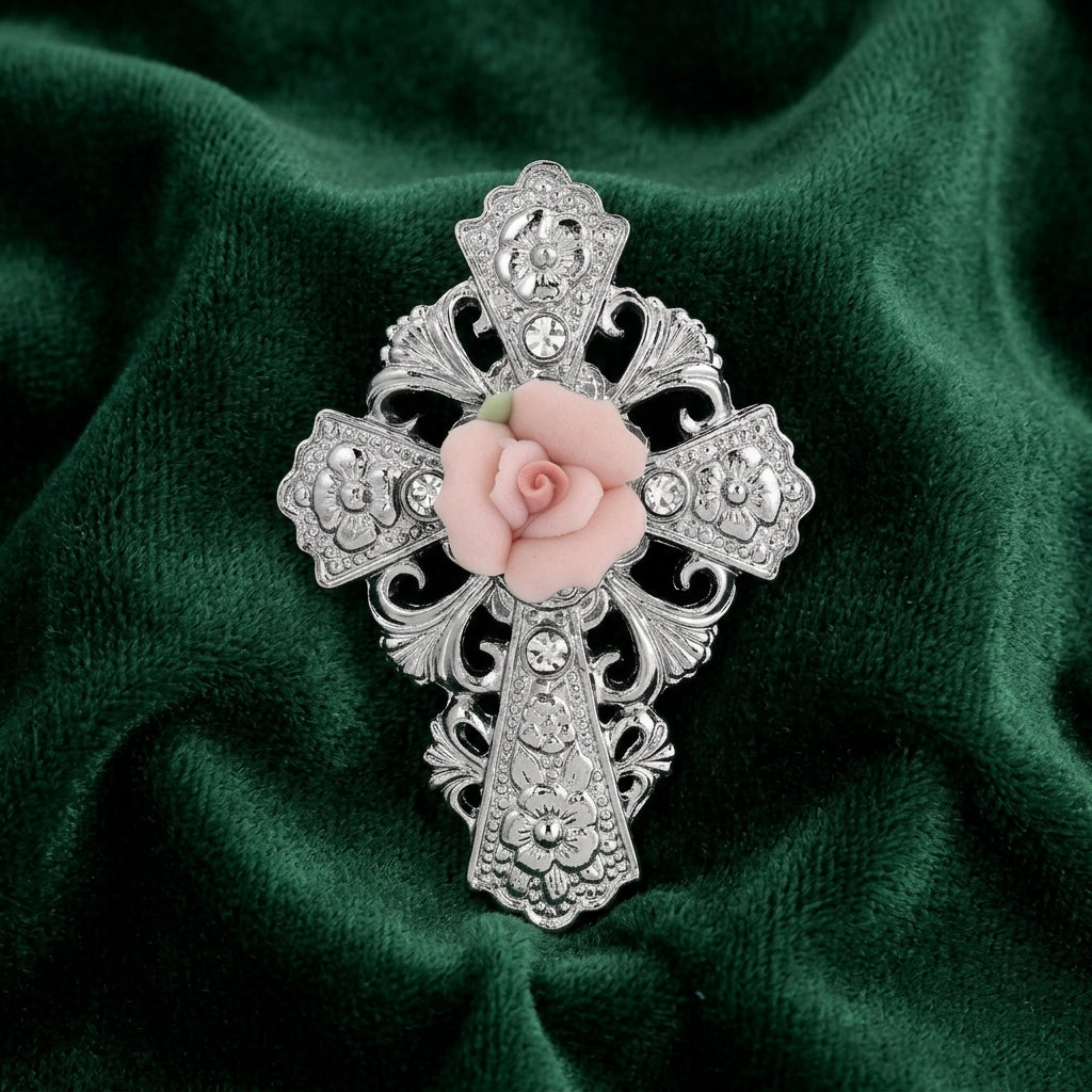 Decorative cross brooch with a pink rose on a green fabric background