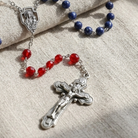 Red White and Blue Glass Bead Crucifix Rosary on a textured linen surface