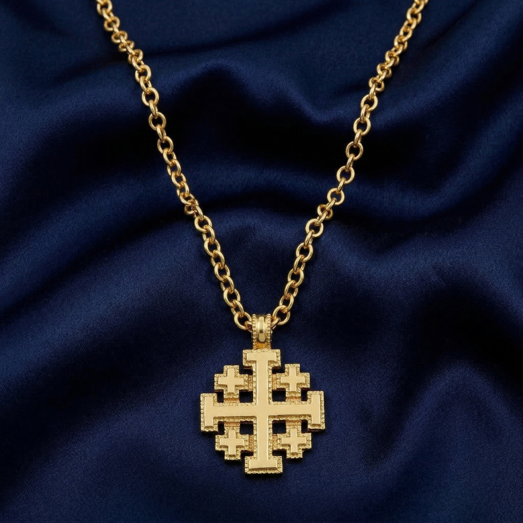 Gold necklace with a Jerusalem cross pendant on a blue fabric background