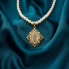 Pearl necklace with a gold Our Lady of Guadalupe pendant on teal fabric