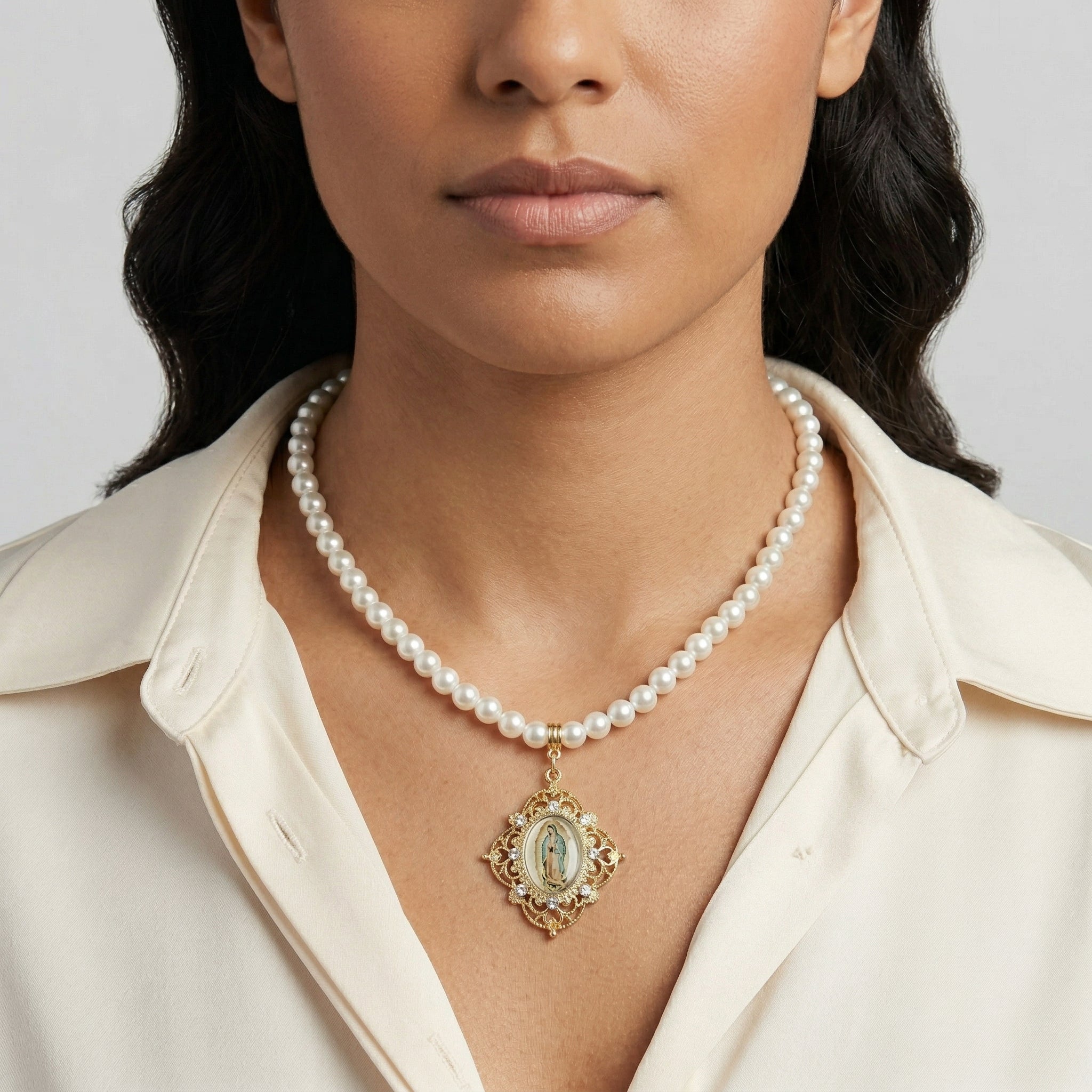 Woman wearing a pearl necklace with Our Lady of Guadalupe against a neutral background