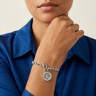 Woman in a blue shirt wearing a silver tone Mother Mary and Child toggle chain bracelet. 
