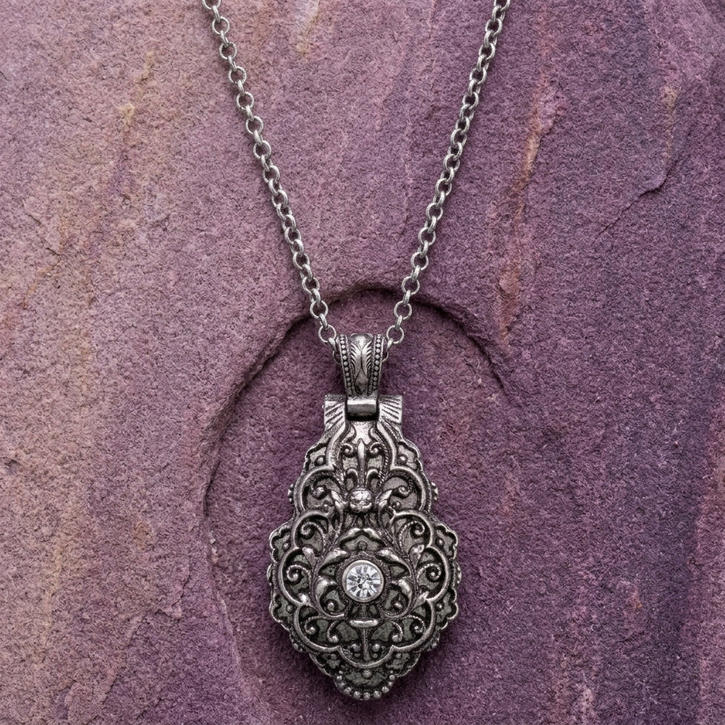 Silver locket pendant necklace on a purple stone background