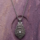 Silver locket pendant necklace on a purple stone background