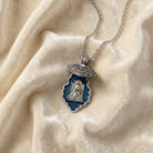 Opened locket necklace with Saint Thérèse of Lisieux religious design on a beige fabric background