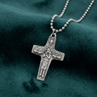 Silver cross pendant necklace on a green fabric background