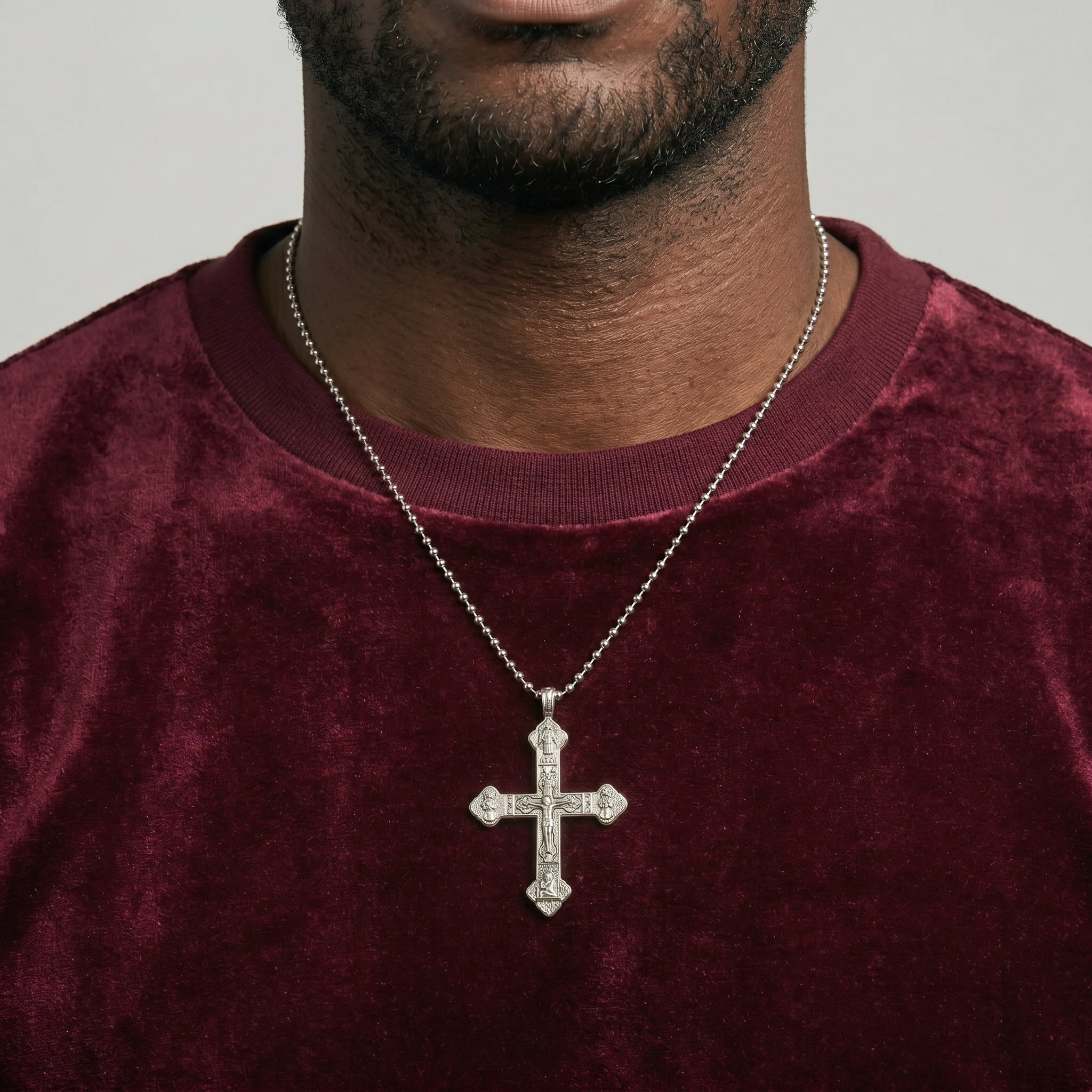 Man wearing a maroon shirt with a silver cross necklace