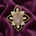 Decorative brooch with religious Mother Mary and Child design on a purple fabric background