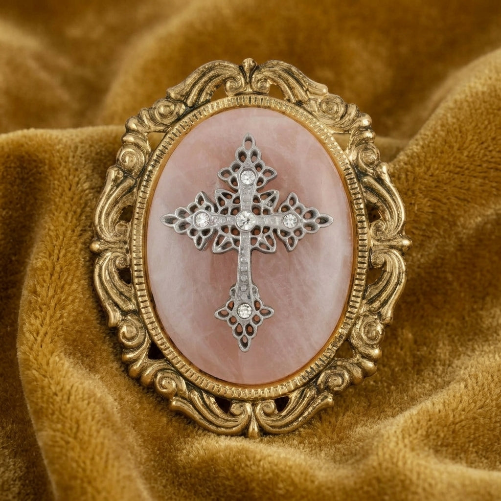 Decorative brooch with cross design on a rose quartz stone, gold frame, on brown fabric background