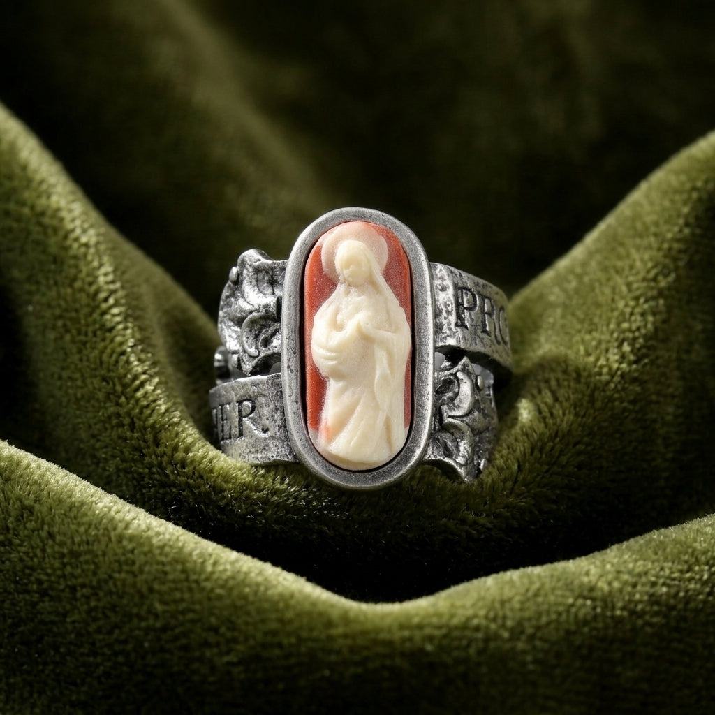 Silver ring with a religious red and ivory cameo on a green fabric background