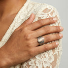 Hand wearing a silver ring with a resin red and ivory cameo resting on a lace garment.