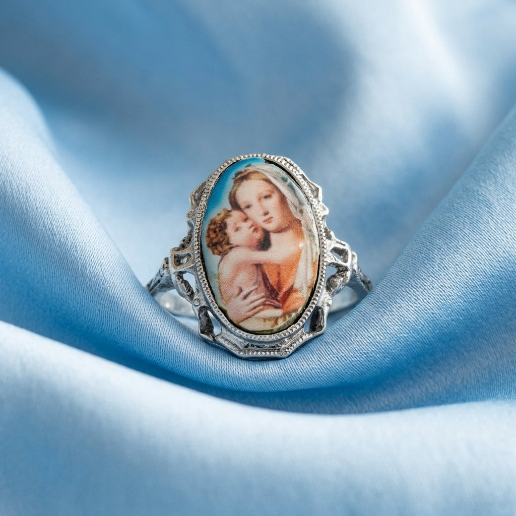 Ring with a decorative Mother Maryand Child design on a blue fabric background