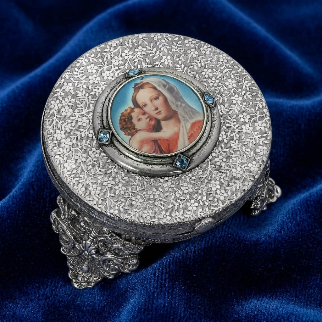 Decorative round silver box with a portrait of Mother Mary and Child on a blue fabric background