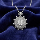 Silver necklace with a detailed bible rosary pendant on a blue velvet background